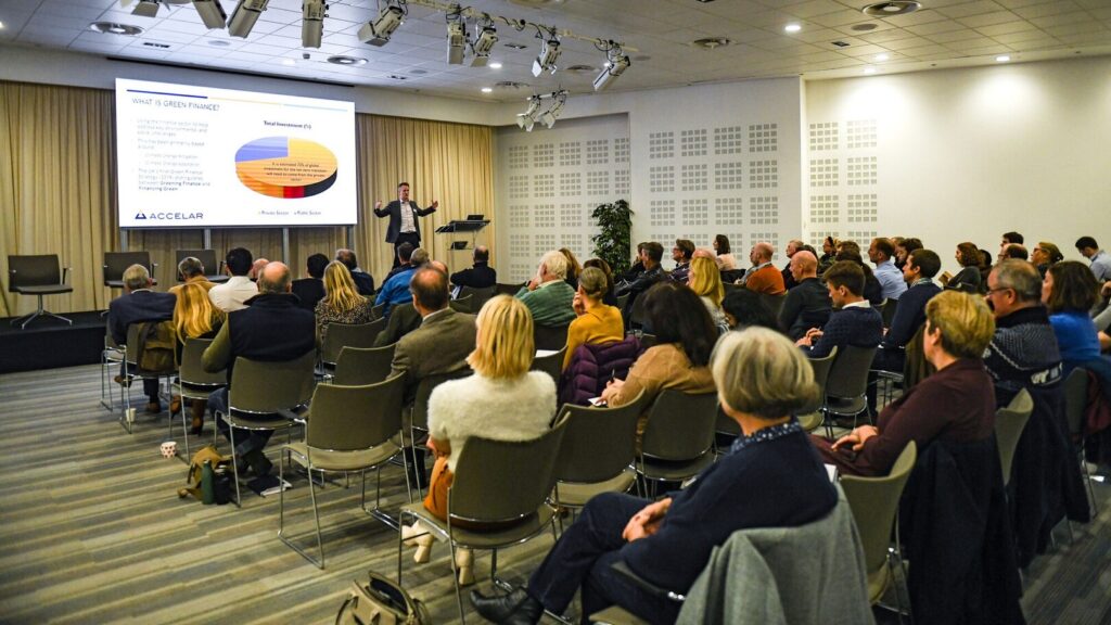 Audience listening to a speaker presenting a slide on green finance in a conference hall