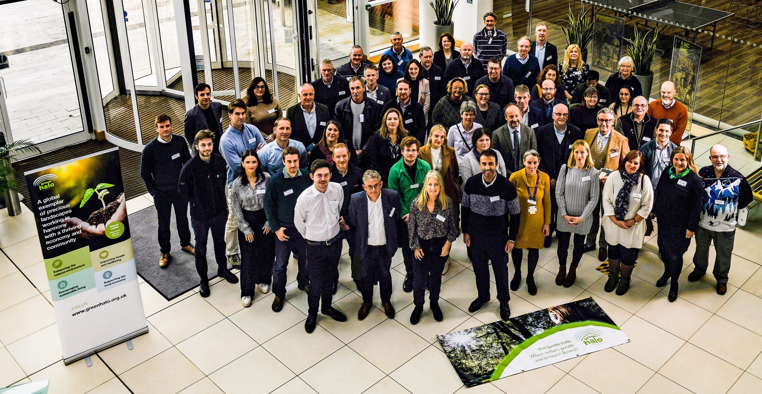 Group of conference attendees posing in an atrium beside Green Halo banners and a roll-up display