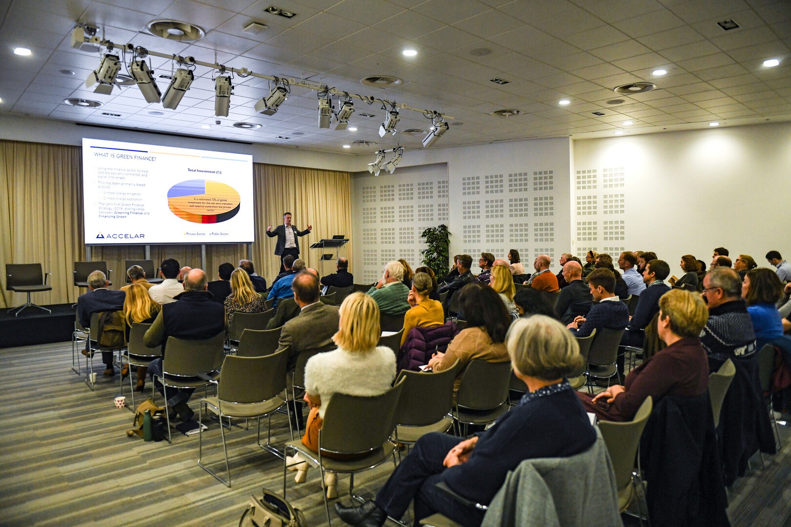Audience seated in conference room as speaker presents green finance slide at Green Halo conference, Ordnance Survey, Southampton